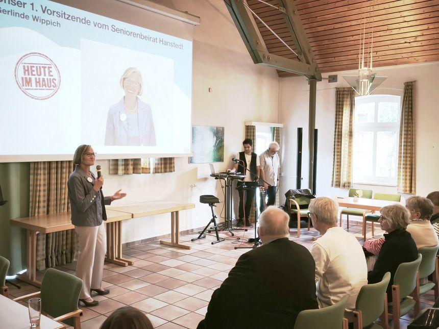 Frau hält Präsentation vor Publikum in einem Saal mit Holzbalkendecke